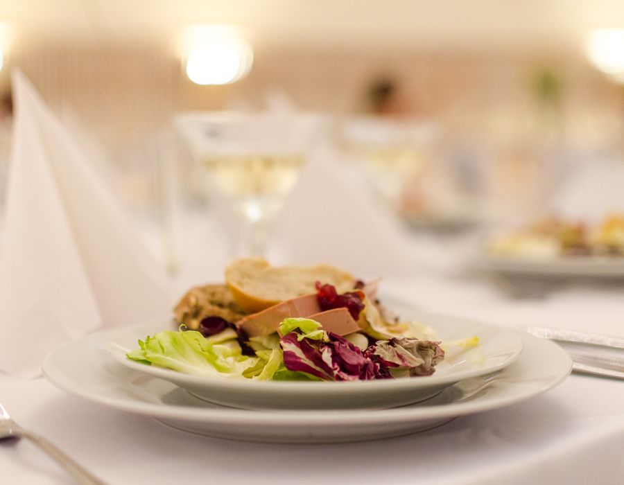 Assiette de poisson et terrine du marché, salade croquante et pousses, dressée dans la lumière tamisée de la salle.