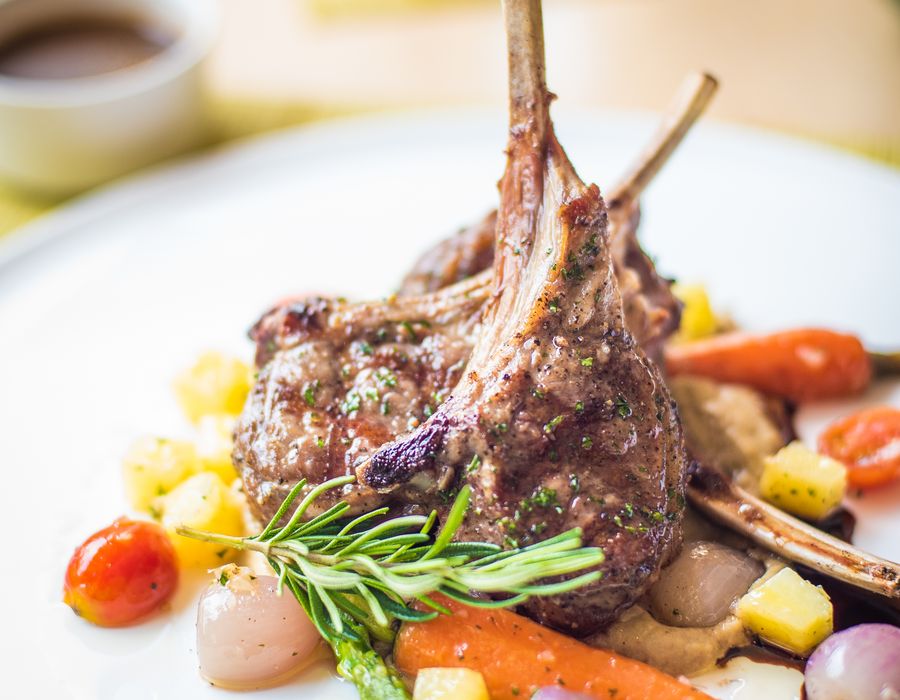 Carré d'agneau rôti rosé, côtes manchonnées, romarin frais et petits légumes glacés, jus court en saucière.